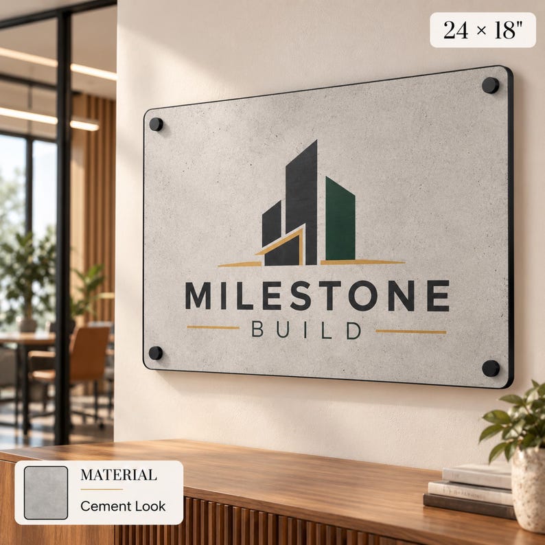 a sign for "Milestone Build" mounted on a wall, with a wooden desk and a plant in the foreground.