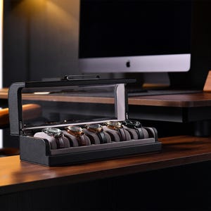 a desk with a computer monitor and a watch in a case