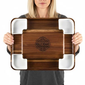 Puede incluir: Una bandeja rectangular de madera con cuatro cuencos esquineros de cerámica blanca. La bandeja tiene un acabado de vetas de madera oscura y un emblema decorativo con el texto "KELLY KEANE HOME MADE".