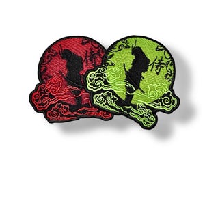 May include: Two embroidered patches featuring a black silhouette of a person standing in front of a red and green moon with clouds. The text "侍" is embroidered on the moon.