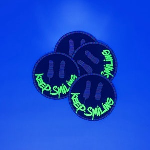 May include: Four black and green round stickers with a smiley face and the text "Keep Smiling" in green.
