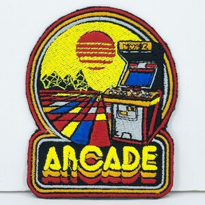 May include: Embroidered patch with a retro arcade game, a sunset, and the word "ARCADE" in a colorful, stylized font.