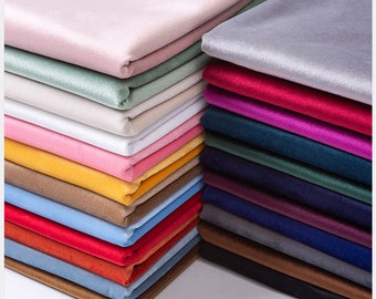 May include: A stack of fabric swatches in various colors, including pink, red, blue, green, yellow, and brown. The fabric is soft and velvety, and the swatches are arranged in a neat pile.