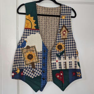 May include: A patchwork vest with a whimsical sunflower theme. The vest features a blue and tan gingham pattern, with appliqued sunflowers, a birdhouse, and a sign that reads "Sunflower". It has a button-up front and a green corduroy trim.