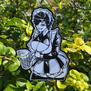 May include: A black and white embroidered patch featuring a stylized illustration of a character wearing a maid outfit with a ruffled headpiece and apron, holding a large beer mug with foam. The design has bold ink-style lines and shading.
