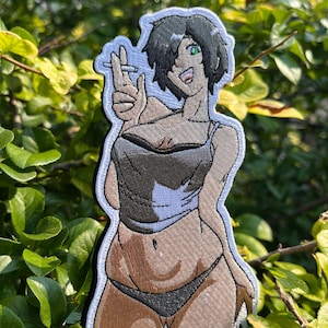 May include: An embroidered patch featuring an anime-style character with short black hair and a green eye. The character wears a dark gray tank top and black underwear, holding a cigarette between two fingers while smiling with an open mouth.