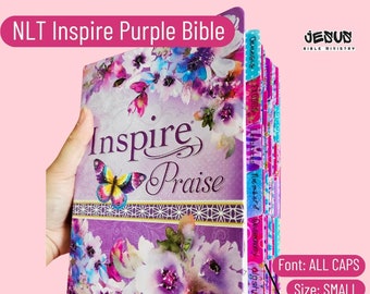 Könnte beinhalten: Eine lilafarbene Bibel mit einem Blumenmuster und den Worten "Inspire Praise" auf dem Einband. Die Bibel hat Registerkarten mit den Namen der Bücher der Bibel, darunter Genesis, Exodus, Leviticus, Numeri, Deuteronomium, Josua, Richter, Rut, 1 Samuel, 2 Samuel, 1 Könige, 2 Könige, 1 Chroniken, 2 Chroniken, Esra, Nehemia, Esther, Hiob, Psalmen, Sprichwörter, Prediger, Hohelied Salomos, Jesaja, Jeremia, Klagelieder, Hesekiel, Daniel, Hosea, Joel, Amos, Obadja, Jona, Micha, Nahum, Habakuk, Zefanja, Haggai, Sacharja, Maleachi, Matthäus, Markus, Lukas, Johannes, Apostelgeschichte, Römer, 1 Korinther, 2 Korinther, Galater, Epheser, Philipper, Kolosser, 1 Thessalonicher, 2 Thessalonicher, 1 Timotheus, 2 Timotheus, Titus, Philemon, Hebräer, Jakobus, 1 Petrus, 2 Petrus, 1 Johannes, 2 Johannes, 3 Johannes, Judas und Offenbarung.