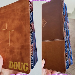 May include: Two brown leather-bound books with gold cross and text details. One book is labeled "DOUG" and "LARGE", the other is labeled "SMALL". Both books have colorful tabs with text. The word "TABS" is at the top.