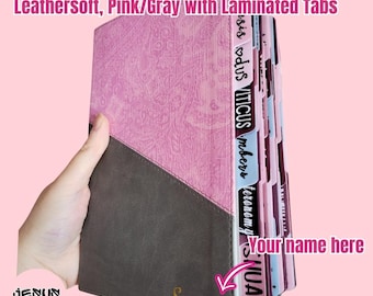 May include: An NIV personal size large print Bible with a pink and gray Leathersoft cover. The cover features a diagonal design with a textured pink upper section and a smooth gray lower section. It includes laminated tabs and the name Suzanne.