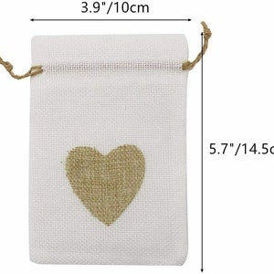 May include: A white burlap drawstring bag with a brown burlap heart in the center. The bag measures 5.7 inches tall and 3.9 inches wide.