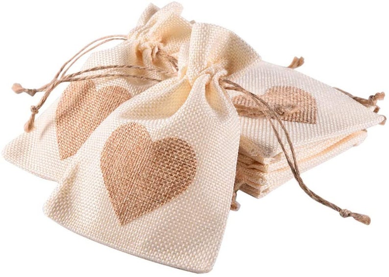 May include: A stack of small, cream-colored burlap bags with brown heart designs. The bags have drawstrings and are perfect for small gifts or favors.