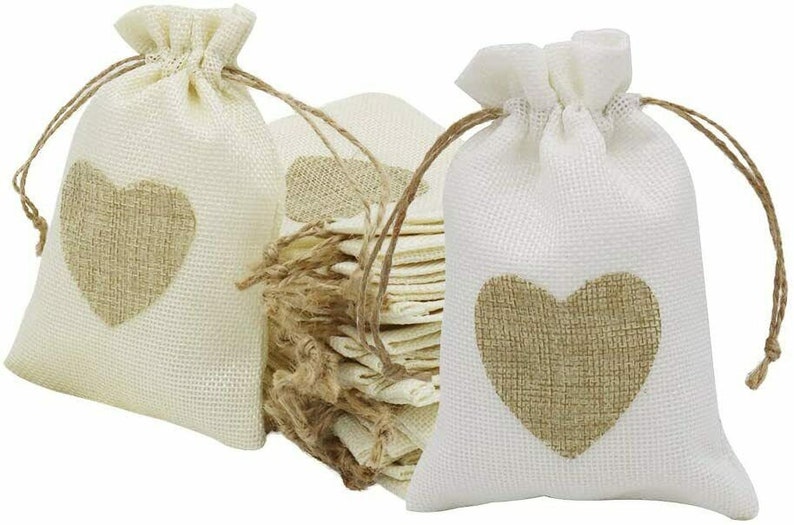 May include: A set of 12 small, white burlap drawstring bags with a brown heart design. The bags are perfect for packaging small gifts or favors.