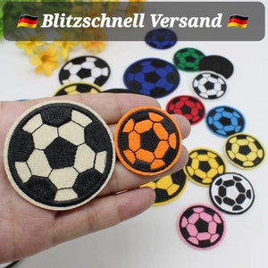 Op de afbeelding: Een verzameling geborduurde strijkpatches met voetballen in verschillende kleuren, waaronder wit, zwart, oranje, blauw, geel, rood en roze. De patches zijn perfect om kleding, tassen of andere stoffen items een sportieve touch te geven.