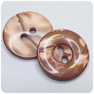 May include: Two brown and gold swirl patterned plastic buttons with two holes each.