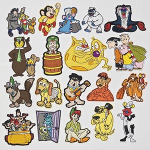 Könnte beinhalten: Eine Sammlung farbenfroher Cartoon-Charakter-Patches, darunter ein Bär, ein Hund und ein Affe. Die Patches sind mit verschiedenen Designs bestickt und sind wahrscheinlich für Kleidung oder Accessoires bestimmt.