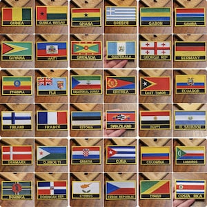 Może przedstawiać: Kolekcja 36 haftowanych naszywek z flagami różnych krajów. Każda naszywka jest prostokątna i ma złotą obwódkę. Flagi są ułożone w sześć rzędów po sześć naszywek.