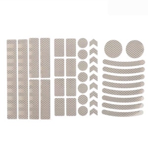May include: A set of reflective stickers for bicycles, including strips, circles, arrows, and curved shapes. The stickers are white and have a diamond pattern.
