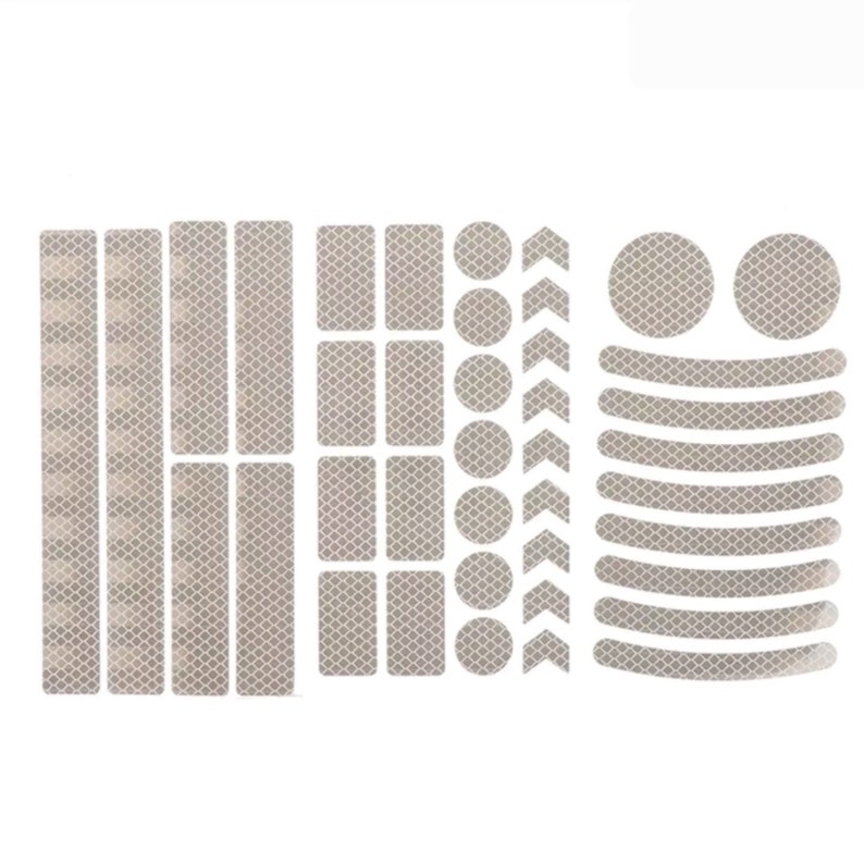 May include: A set of reflective stickers for bicycles, including strips, circles, arrows, and curved shapes. The stickers are white and have a diamond pattern.
