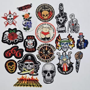 May include: A selection of embroidered patches with skull motifs, roses, and text. Designs include a skull with a rose, a skull giving the middle finger, and the words "BAD BOYS". The patches are in various colours, including red, black, and white.