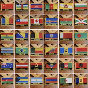 May include: A collection of 48 embroidered fabric patches featuring flags of different countries. Each patch has a gold border and a black background with the country name printed in white.
