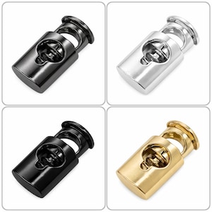 May include: Four metal cord locks in a square grid. The cord locks are in black, silver, and gold. Each cord lock has a cylindrical body with a spring mechanism and a hole for a cord. The cord locks are designed to secure cords.