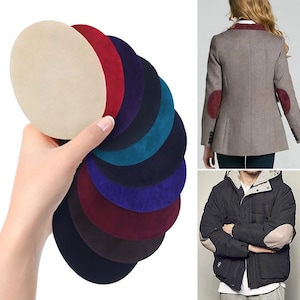 Könnte beinhalten: Sortiment aus zehn runden Ellbogenflicken aus Wildleder in verschiedenen Farben, darunter Beige, Rot, Türkis, Marineblau, Lila, Burgunderrot und Schwarz. Die Flicken sind fächerförmig angeordnet, wobei der beigefarbene Flicken oben liegt.