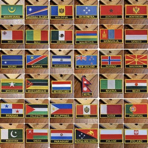 Può includere: Una collezione di 40 toppe di stoffa ricamate con bandiere di diversi paesi. Le toppe sono rettangolari e hanno un bordo giallo. Ogni toppa presenta la bandiera di un paese diverso con il suo nome stampato sotto.