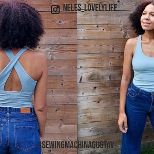May include: A light blue ribbed tank top with a criss-cross back detail. The top is paired with blue denim jeans. The image is split into two panels, showing the front and back of the outfit. The background is a wooden wall.