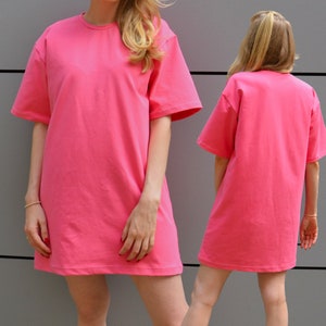 May include: A pink oversized t-shirt dress with short sleeves. The dress is made of a soft, comfortable fabric and has a relaxed fit.