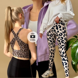 Peut inclure: Ensemble de soutien-gorge de sport et de leggings à imprimé léopard. Le soutien-gorge de sport a un design croisé dans le dos. Les leggings ont un fond beige avec des taches noires. Un sweat-shirt blanc et un sweat à capuche zippé violet sont également visibles.
