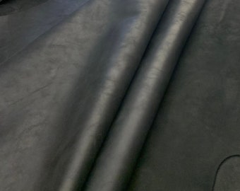 May include: A close-up of a black leather hide. The leather is folded in half and has a smooth, slightly textured surface.