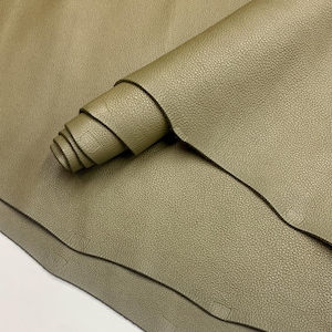 Peut inclure: Peau de cuir vert olive, partiellement enroulée, avec une surface texturée. Le cuir a une finition mate et semble souple. L'image montre le grain naturel et de subtiles variations de couleur, suggérant un matériau de haute qualité adapté à divers projets d'artisanat.