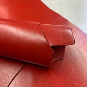 May include: A close-up of a red leather sheet folded over itself. The leather has a smooth, glossy finish.