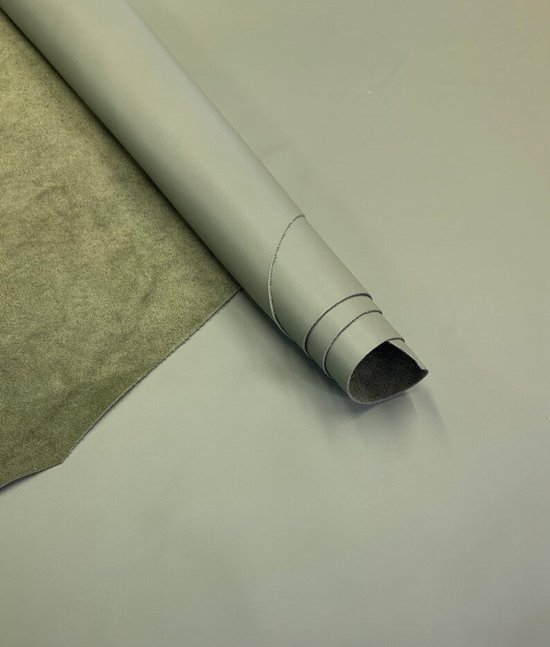May include: A roll of light green leather with a suede backing. The leather is rolled up and the suede is visible on the inside of the roll.
