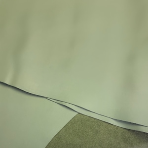 May include: Close-up of a light gray leather material. The leather is folded over itself, showing the smooth texture.