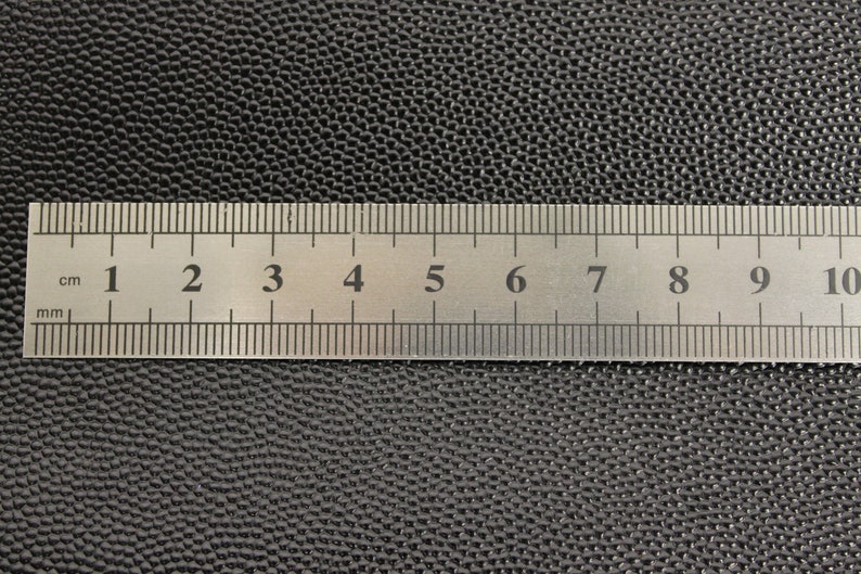 Op de afbeelding: Een close-up van een zilveren liniaal met zwarte markeringen. De liniaal is gemarkeerd in centimeters en millimeters. De liniaal is 10 centimeter lang.