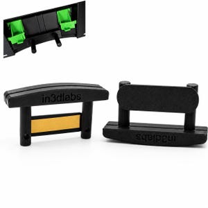 Può includere: Due supporti da parete in plastica nera con il testo in3dlabs stampato sul davanti. Un supporto presenta una striscia adesiva gialla sul retro, mentre l'altro mostra una superficie nera testurizzata. In alto si vedono clip verdi e perni neri.