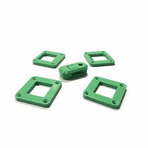 May include: Five green, geometric objects are arranged on a white background. Four are square with a central opening and rounded corners. The fifth is a small, rectangular object with a hinged design. All objects are a solid, bright green color.