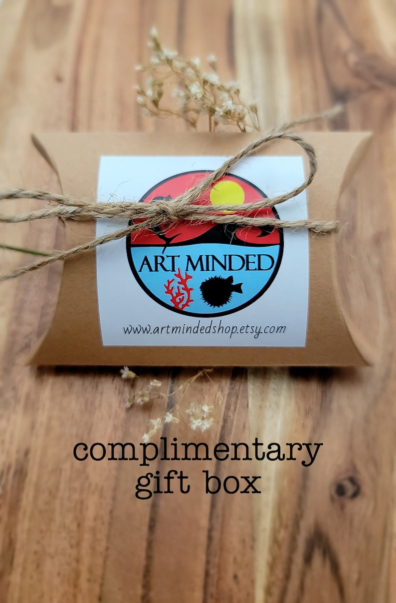 May include: A brown cardboard pillow-style gift box tied with natural twine. A circular sticker features a red and blue design with a yellow sun, a black fish, and red coral, with the text ART MINDED and www.artmindedshop.etsy.com printed below.