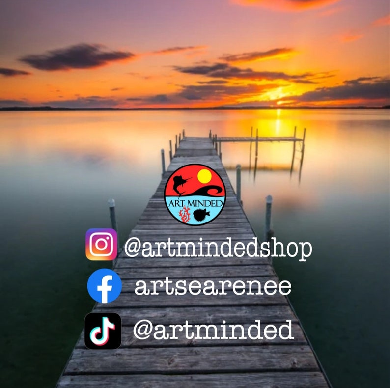 May include: A wooden pier extending into a calm lake at sunset with a circular logo featuring a sun, fish, and coral, plus social media handles: @artmindedshop, artsearenee, and @artminded displayed in white text with corresponding icons.