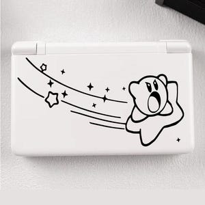 Puede incluir: Consola de juegos portátil blanca con un gráfico de dibujos animados en blanco y negro de un personaje con forma de estrella. El gráfico incluye estrellas y líneas, sugiriendo movimiento. La consola es rectangular.