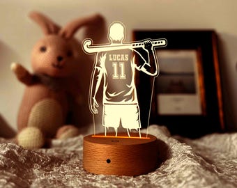 Könnte beinhalten: Ein Holzsockel mit einem leuchtenden 3D-Design eines Hockeyspielers, der einen Schläger hält. Der Spieler trägt ein Trikot mit dem Namen "Lucas" und der Nummer "11" auf dem Rücken.