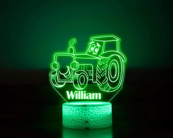 May include: Green tractor-shaped night light with a smiling face and the name "William" printed below. The light is on a white base with a textured surface.