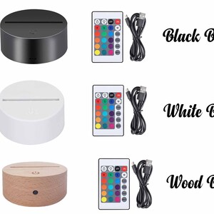 May include: Three images showing a 3D LED night light with a remote control and USB cable. The first image shows a black base, the second image shows a white base, and the third image shows a wood base.