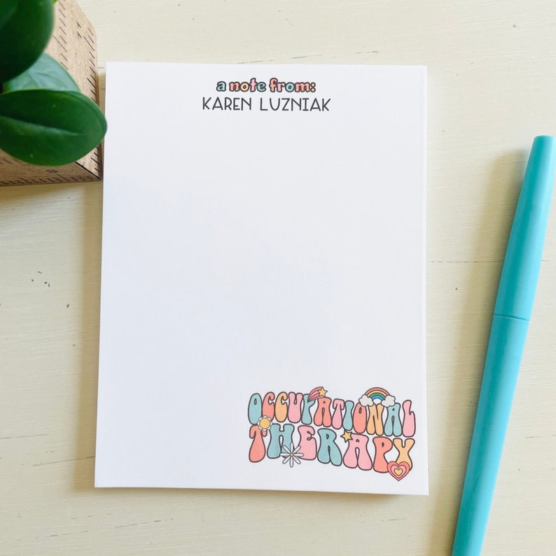 Peut inclure: Un bloc-notes blanc avec le texte "a note from: KAREN LUZNIAK" en haut et le texte "OCCUPATIONAL THERAPY" en police r&eacute;tro color&eacute;e en bas. Le bloc-notes a un arc-en-ciel, une &eacute;toile, un soleil et un c&oelig;ur graphique.