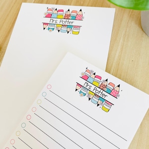 May include: Two white notepads featuring a colourful pencil and floral design. The top notepad is blank, while the bottom one has lined paper and coloured circles. The text "Mrs. Potter" is printed on both notepads.