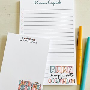 Peut inclure: Un bloc-notes blanc avec une page lign&eacute;e et une note de Karen Luzniak. Le bloc-notes a un graphique color&eacute; qui dit "Jouer est mon occupation pr&eacute;f&eacute;r&eacute;e".