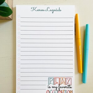 Peut inclure: Un bloc-notes blanc avec un design lign&eacute; noir et blanc. Le bloc-notes porte un nom personnalis&eacute; en haut, "Karen Luzniak". Le bas du bloc-notes comporte un graphique color&eacute; qui dit "PLAY is my favorite OCCUPATION".
