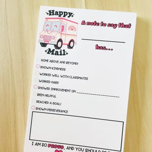 May include: A white notepad with a pink and beige mail truck illustration. The notepad has the words "Happy Mail" and "A note to say that has..." printed on it. It includes checkboxes for various achievements and a space for a personalized message.
