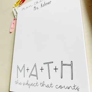 May include: White notepad with black text that reads "From the Mrs. Kohner" at the top and "M+A+T+H the subject that counts" at the bottom.